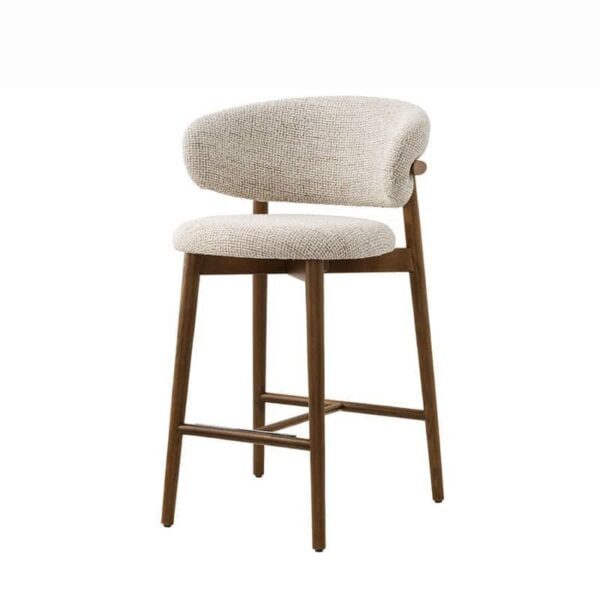 The Caelina bar stool, a contemporary piece featuring a sturdy wooden frame with a light brown finish. It has a curved backrest and a cushioned seat upholstered in a light, textured fabric, providing both comfort and style. The bar stool is viewed from the front left angle, showcasing its elegant design and smooth lines.