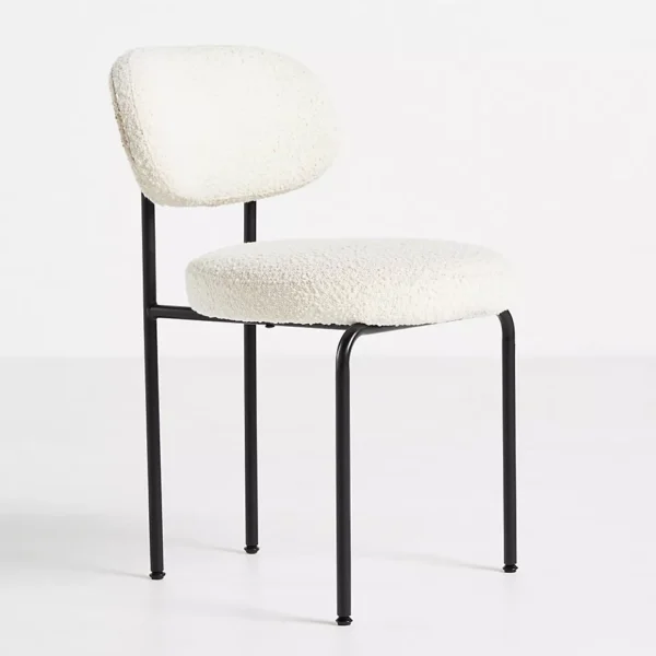 Angled view of a modern dining chair with white boucle upholstery and black metal legs.