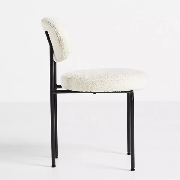 Side view of a modern dining chair with white boucle upholstery and black metal legs.