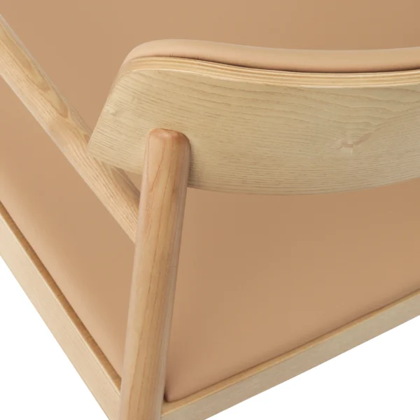 Close-up view of the backrest of a Tobi dining armchair with light natural wood finish and beige upholstered seat