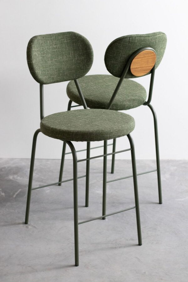 2 Marisol steel bar chairs placed next to each other, one showing the front and the other showing the rear.Both bar chairs are painted in green, and upholstered with a green fabric.