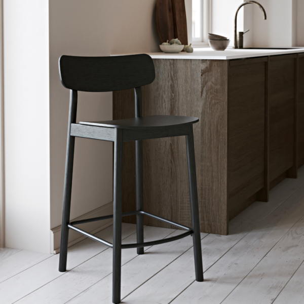 Yuri counter stool in a stylish kitchen setting, featuring a black ash veneer seat and solid ash legs, elegantly placed by a light wood kitchen counter, adding a touch of modern sophistication