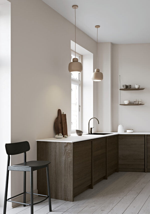 Yuri counter stool in a stylish kitchen setting, featuring a black ash veneer seat and solid ash legs, elegantly placed by a light wood kitchen counter, adding a touch of modern sophistication