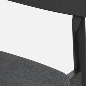 Close up of yuri dining chair, unupholstered in black oak showcasing meticulous joinery and beautiful oak grain