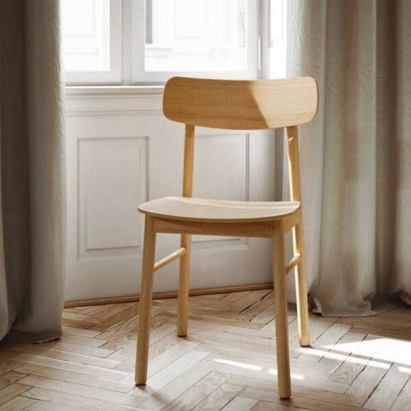 Yuri dining chair in oiled oak, set in front of a a window with natural light showcasing the oak grain