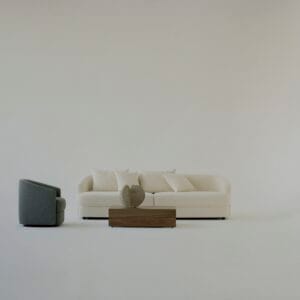 The "Sophie" sofa in off-white stands alongside a grey armchair, with a wooden coffee table in front, creating a minimalist and balanced living room arrangement.