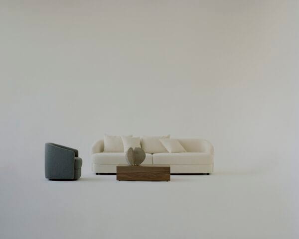 The "Sophie" sofa in off-white stands alongside a grey armchair, with a wooden coffee table in front, creating a minimalist and balanced living room arrangement.