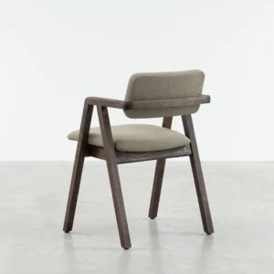Jude in an angled position, jude is made out of solid oak , stained in a walnut finish and and cushioned seat and backrest upholstered in a boucle fabric