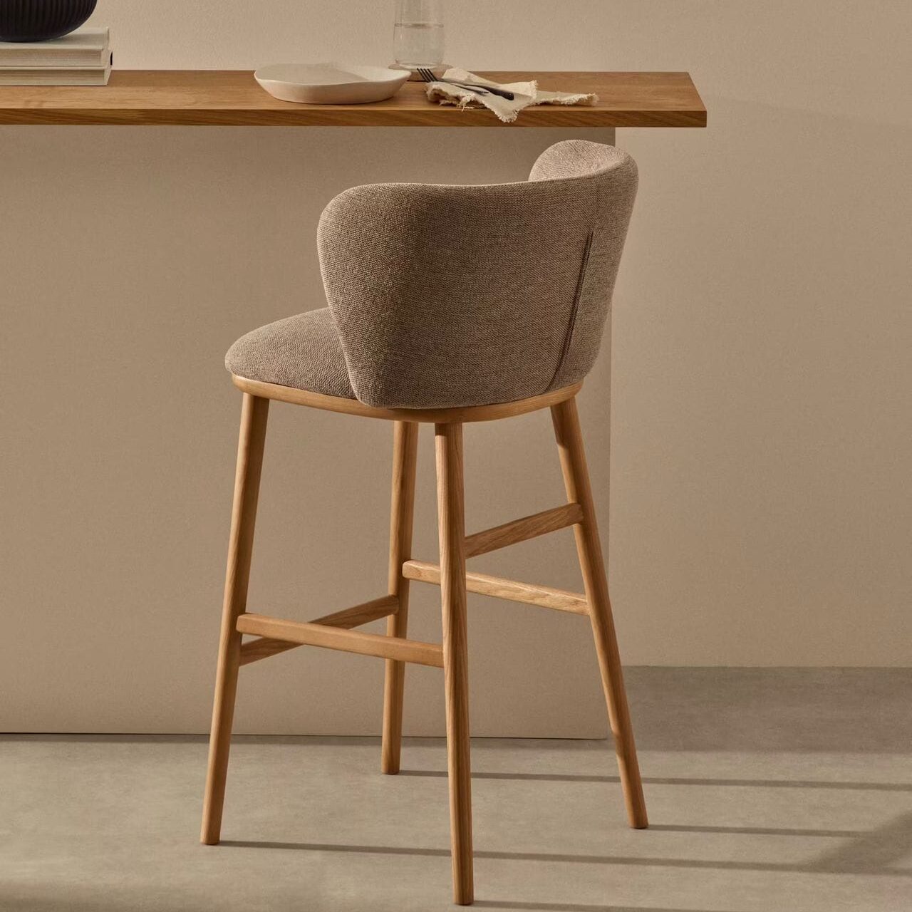 Rear angled view of Q wooden bar chair in front of a bar