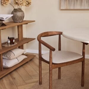 Angled front view of the Emma dining chair, finished in a walnut hue, placed in a serene interior