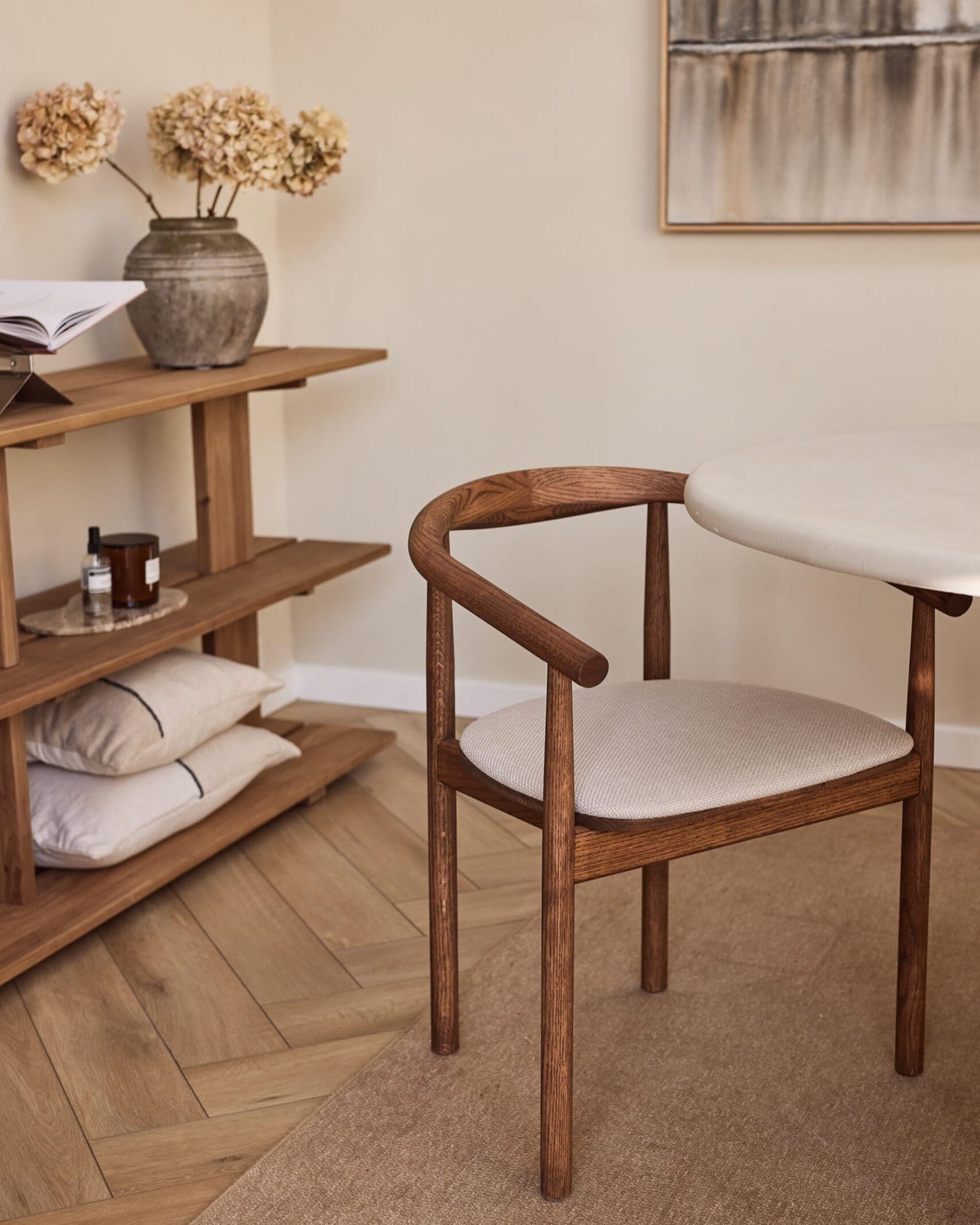 Angled front view of the Emma dining chair, finished in a walnut hue, placed in a serene interior
