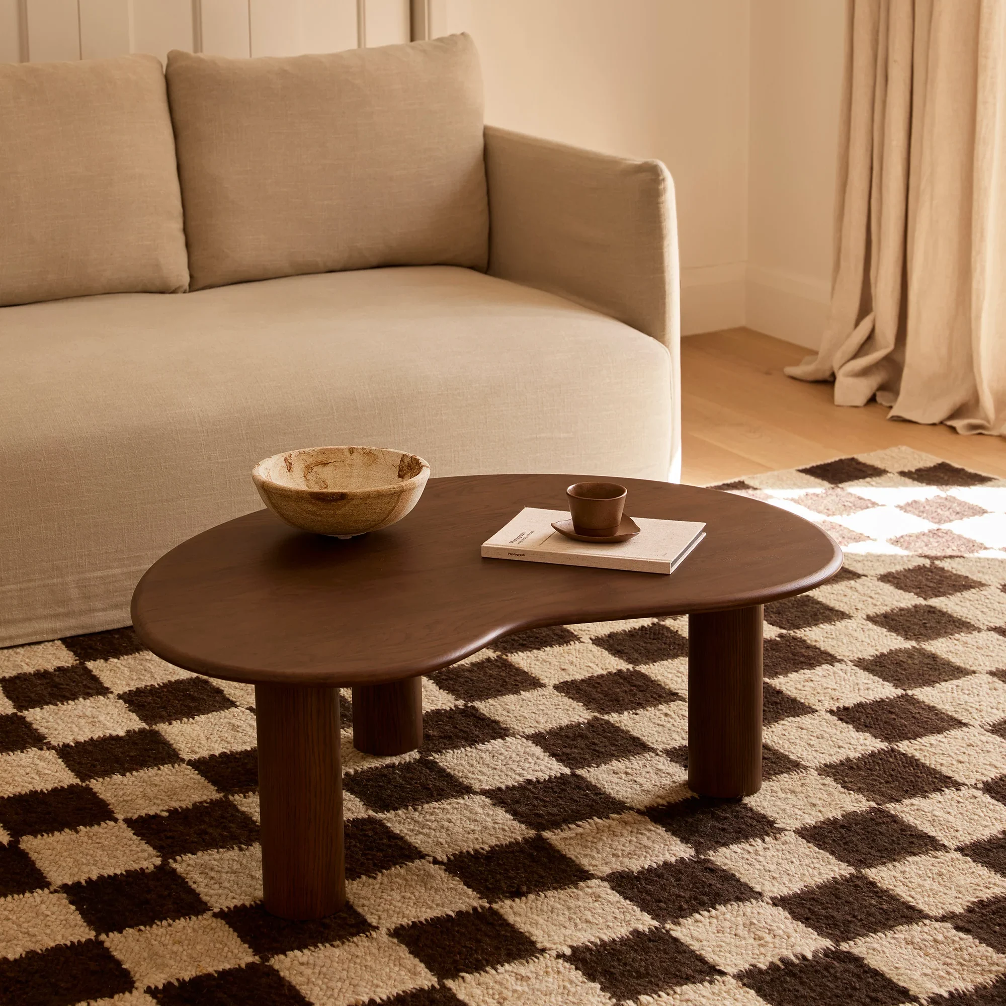 Olly coffee table , organic table top shape, resting on 3 cylindrical legs, handcrafted in solid oak and oak veneer finished in a walnut stain by kersetna in lebanon
